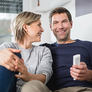 Glückliches junges Paar auf der Couch mit Becker Rollladen-Fernsteuerung