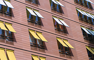 Hausfront eines Mehrfamilienhauses mit Fenstern mit Fallarmmarkisen