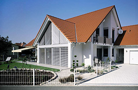 modernes Haus mit großer Fensterfront in der Dachgaube mit Schrägraffstores