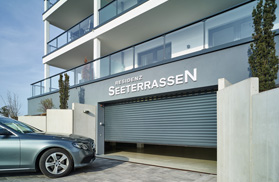 Haus mit Garage. Auto fährt auf Garage zu, die sich öffnet