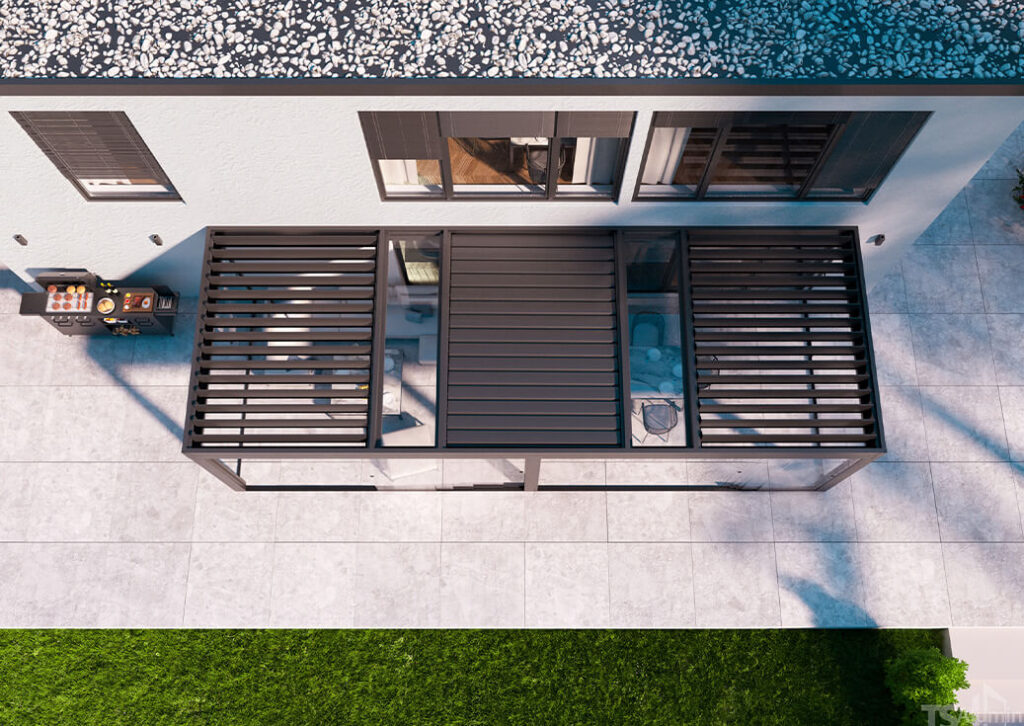 Luftaufnahme einer modernen Terrasse mit einer schwarzen Pergola von „Terrassendächer“, die an ein weißes Haus angebaut ist; mit verstellbaren Lamellen, darunter stehenden Gartenmöbeln und einem Grill auf der gefliesten Terrasse neben einem schmalen Streifen grünem Rasen.