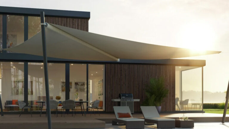 Ein modernes Haus in Bochum mit einem großen, dreieckigen Sonnensegel über einer Holzterrasse, auf der Liegestühle und ein Essbereich im Freien stehen.